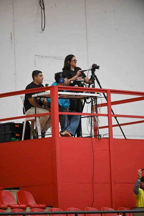 Equipe operando câmeras em plataforma elevada no ginásio
